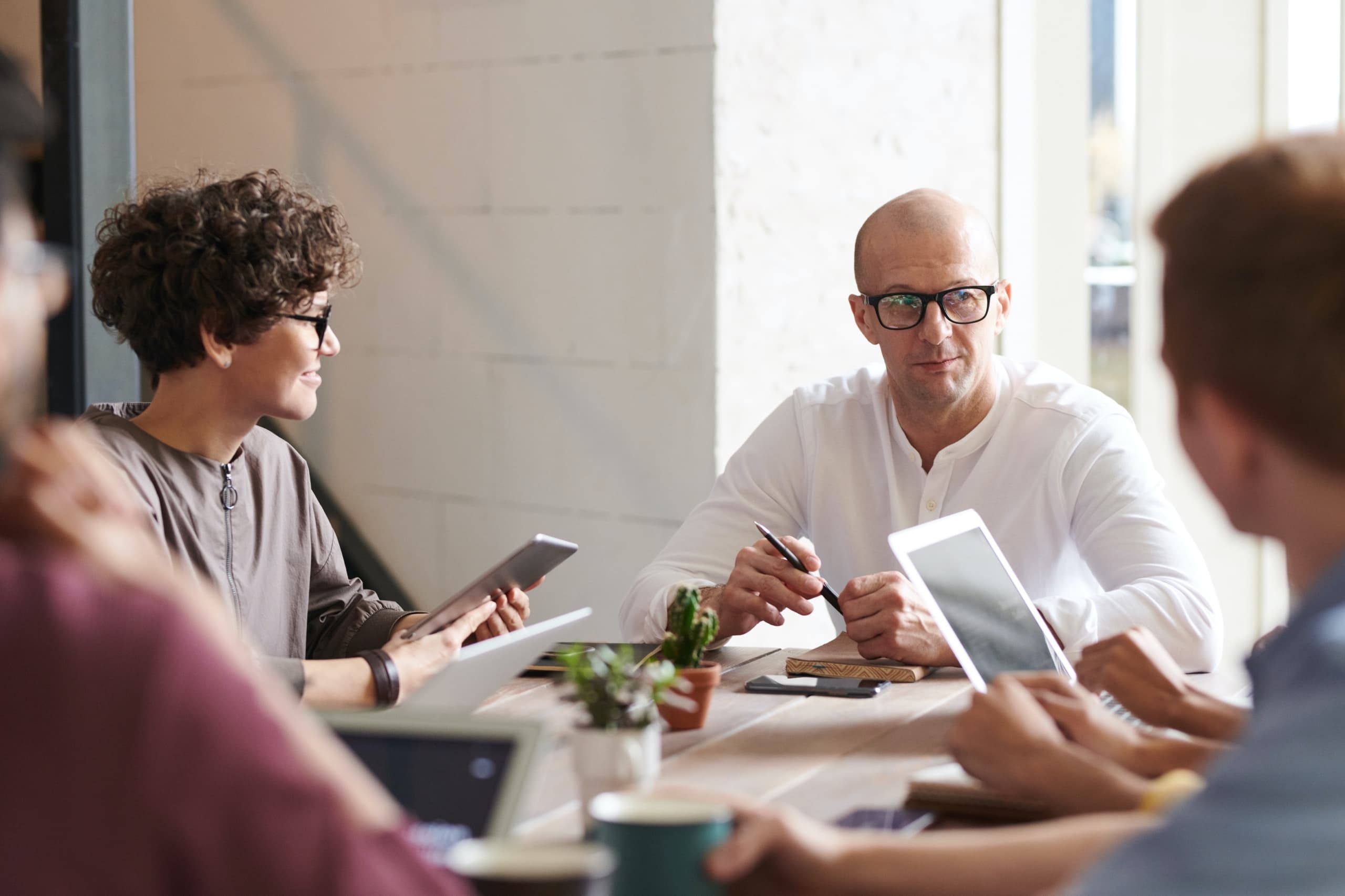 Team sitting around a table, focus is on two team members