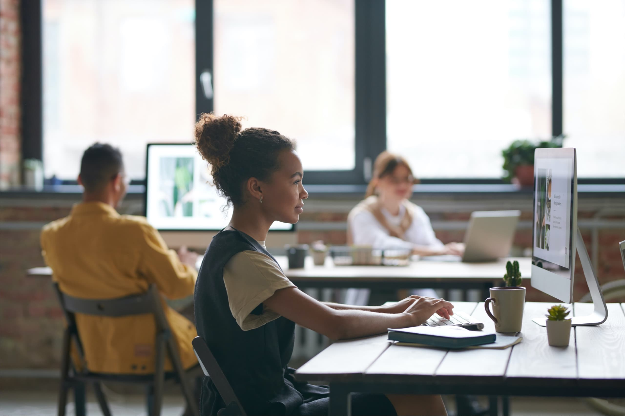 Woman working at a computer, team is sitting behind her