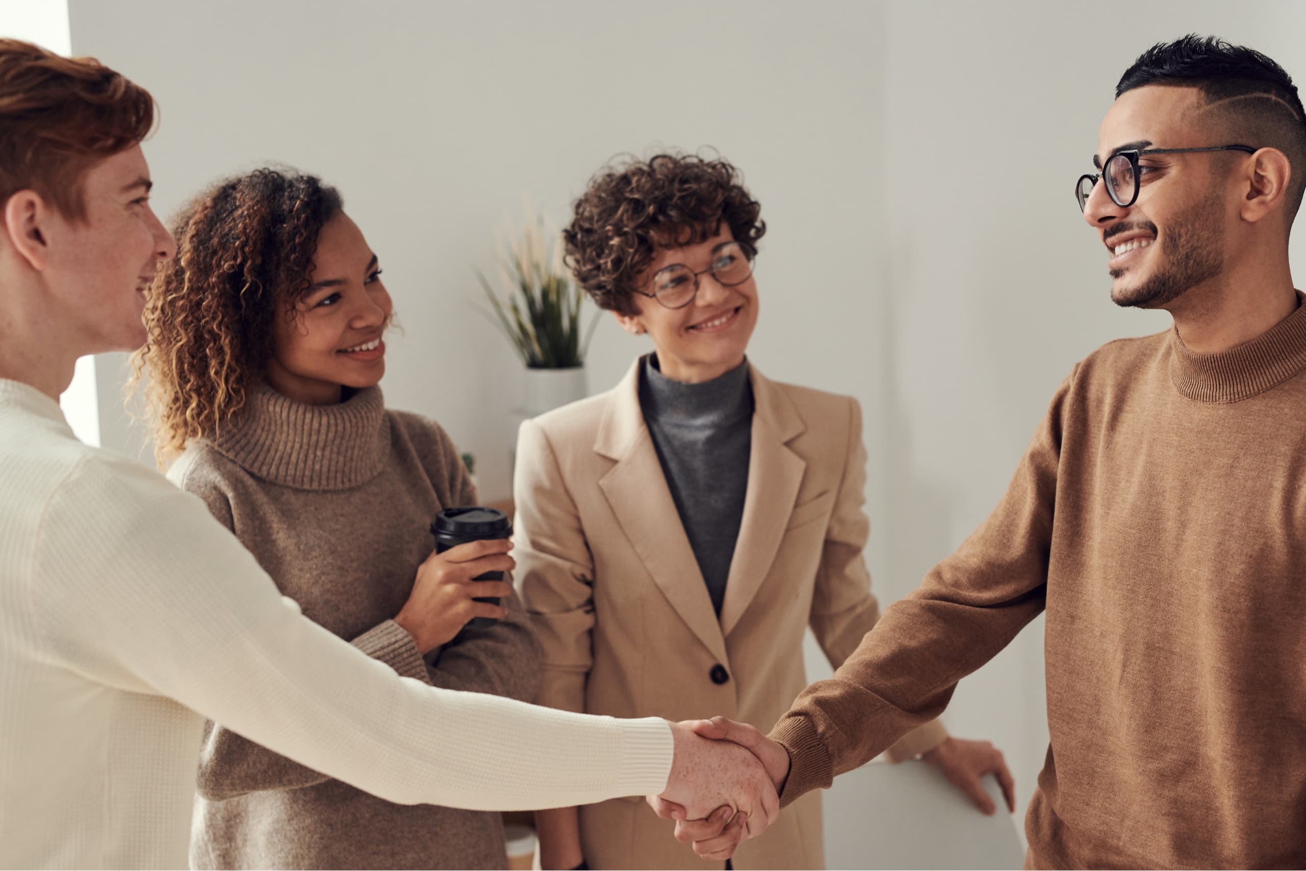 Two colleagues shaking hands while two other colleagues watch