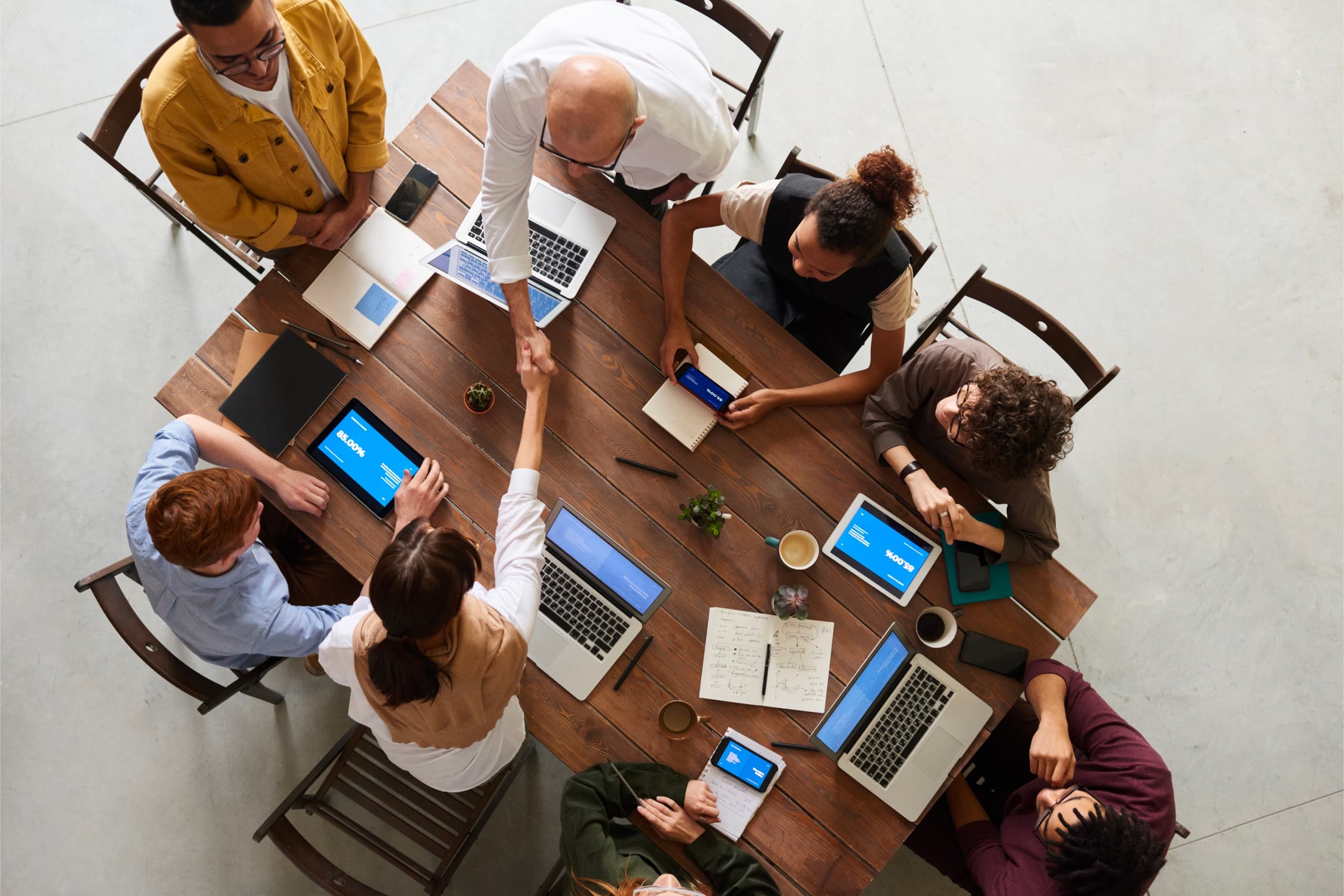 Team sitting around the table, two colleagues are shaking hands